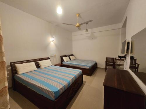 a bedroom with two beds and a flat screen tv at Pearl City Hotel & Yala Safari in Tissamaharama