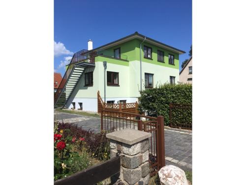 a green and white house with a wooden fence at Haus Pröse mit 2 Ferienwohnungen, 15 Minuten zur Ostsee in Ostseebad Koserow
