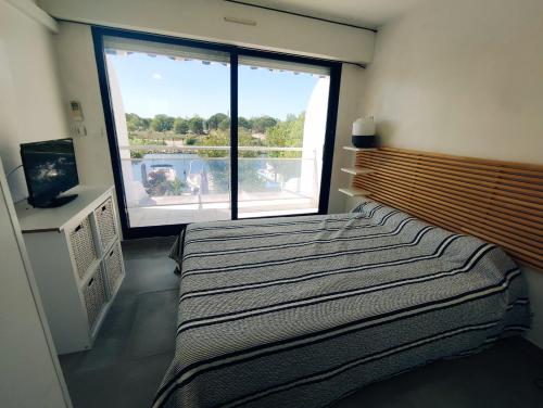 une chambre avec un lit et une grande fenêtre dans l'établissement Marina Maëva Privé, au Grau-du-Roi