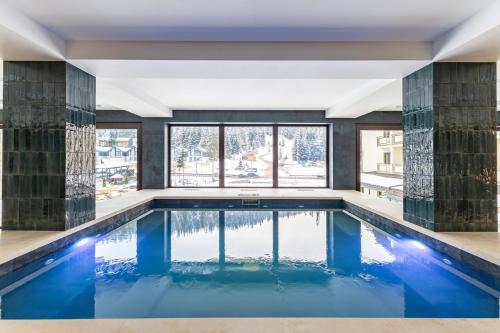 a pool with blue water in a room with windows at Continental SPA Resort in Bukovel
