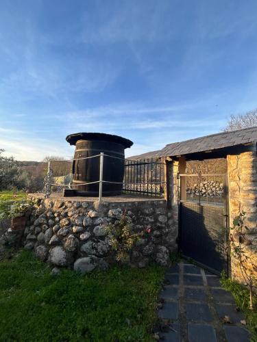 a building with a stone wall next to a fence at As Tres Irmas in Candeleda