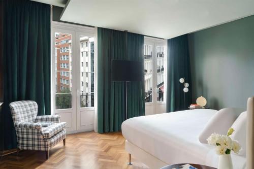 a bedroom with green curtains and a bed and a chair at NH Collection Buenos Aires Lancaster in Buenos Aires