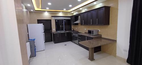 a kitchen with wooden cabinets and a white refrigerator at Laperla luxury family apartment 4 in Amman