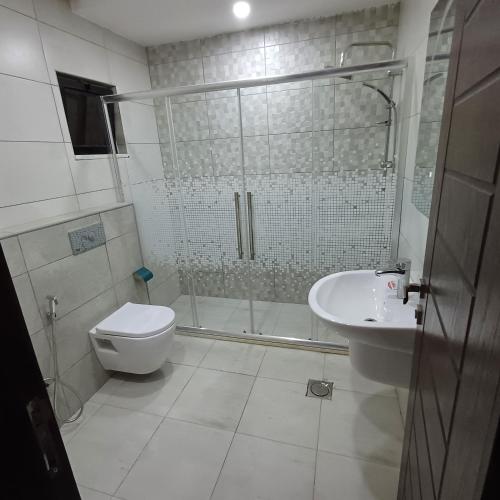 a bathroom with a shower and a toilet and a sink at Laperla luxury family apartment 4 in Amman