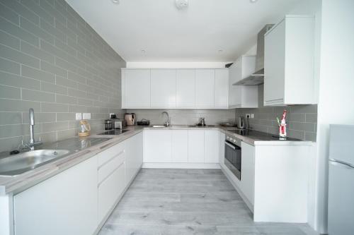 a white kitchen with white cabinets and appliances at Spacious Duplex Apartment - Perfectly Situated in the Heart of the City in Blackpool