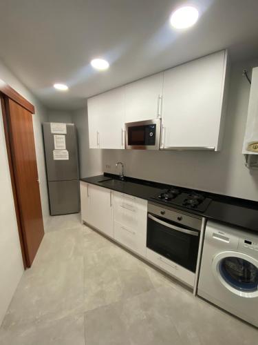 a kitchen with white cabinets and a stove at GranVia Fira Apartment in Hospitalet de Llobregat