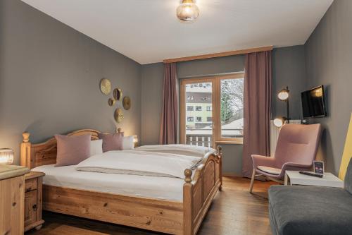 a bedroom with a bed and a chair and a window at B&B Berglift direkt an der Talstation in Bad Hofgastein