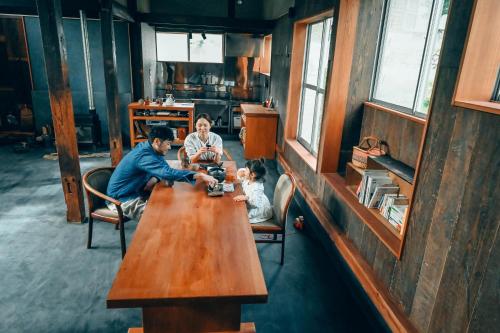 a man and a woman sitting at a wooden table at ツギハギの家 in Itoigawa