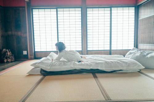a woman laying on a bed in a room at ツギハギの家 in Itoigawa