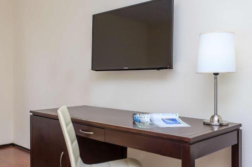 a desk with a lamp and a television on a wall at NH Coatzacoalcos in Coatzacoalcos