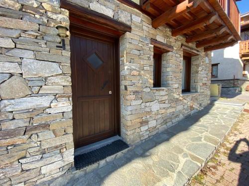 a stone building with a wooden door on it at Baita Arianna BILOCALE FRAITEVE in Sestriere