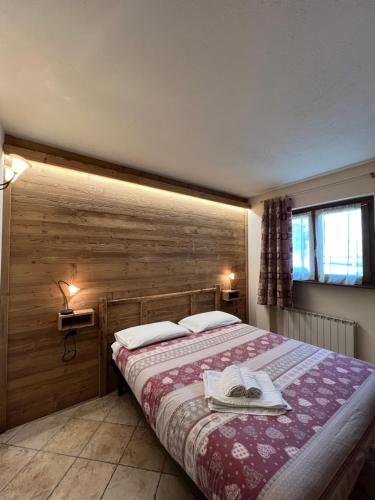 a bedroom with a bed with a wooden wall at Baita Arianna BILOCALE FRAITEVE in Sestriere