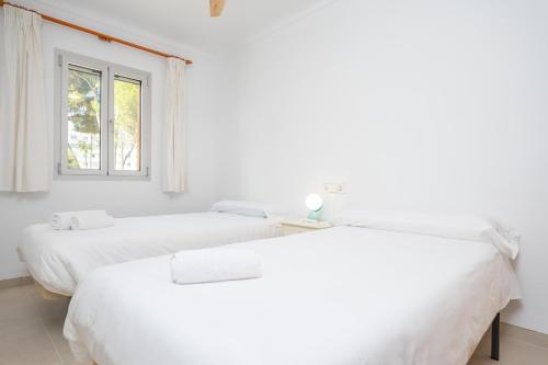 two beds in a white room with a window at Albers in Playa de Muro