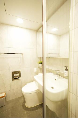 a white bathroom with a toilet and a sink at Wellstay hotel Incheon in Incheon