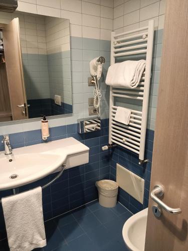 a blue tiled bathroom with a sink and a mirror at Hotel Mercure Venezia-Marghera in Marghera