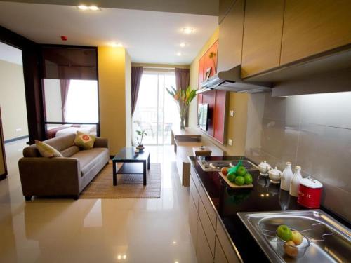a kitchen and living room with a couch and a table at The Grand Wipanan Residence in Chiang Mai