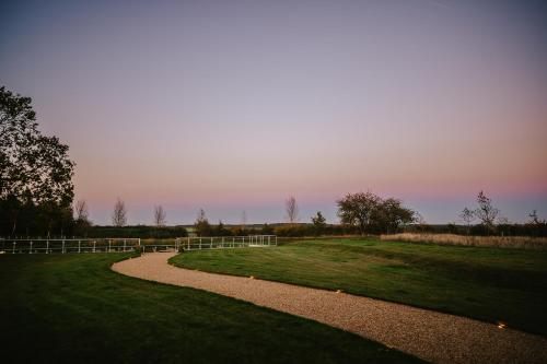 a path in a grassy field with a fence at Nest Farmhouse in Docking