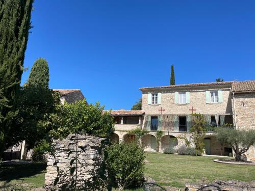 un grand bâtiment en pierre avec des arbres devant lui dans l'établissement Mas des trois citernes, à Saint-Jean-de-Maruéjols-et-Avéjan