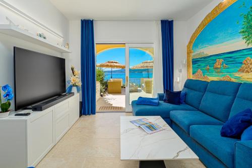 a living room with a blue couch and a flat screen tv at Appartamento Vista Marina direttamente sulla spiaggia con vista mare in Golfo Aranci