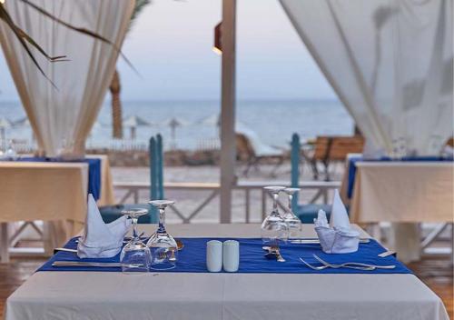 a table with wine glasses and napkins on a blue table cloth at Tropitel Dahab Oasis in Dahab