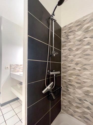 La salle de bains est pourvue d'une douche et d'un mur noir. dans l'établissement Appart RDC - 4pers - Clim - Piscine, à Fitou