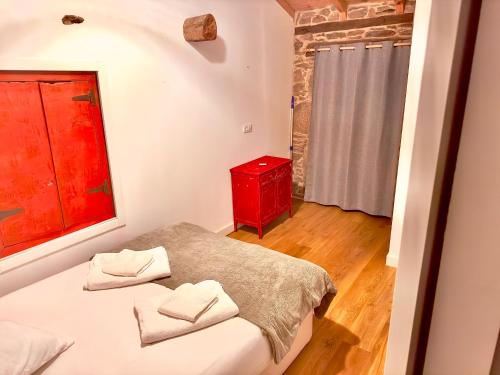 a small bedroom with a bed and a red cabinet at Lagar de Guxeva in Chantada