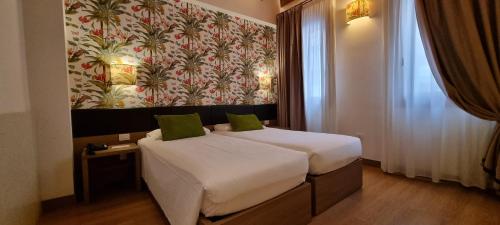 a bedroom with a bed with white sheets and green pillows at UNAHOTELS Eco Hotel Villa Costanza Venezia in Mestre