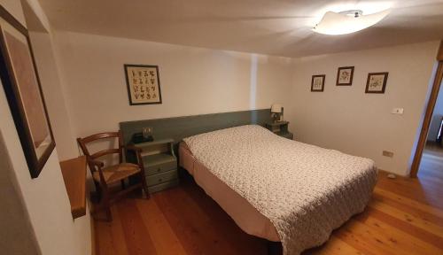 a bedroom with a bed and a table and a chair at Dolomites Holiday Home in Rivamonte