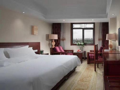 a bedroom with a large white bed and a desk at Vienna International Hotel Xi'an Dayan Tower in Xi'an