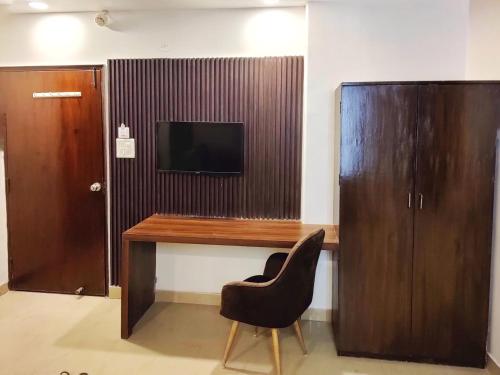 a desk with a chair and a television on a wall at Aditya inn Delhi Airport in New Delhi