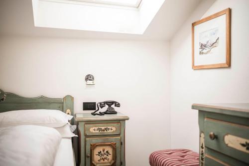 a bedroom with a bed and a phone on a table at Hotel Cavallino D'Oro Bed&Breakfast in Castelrotto
