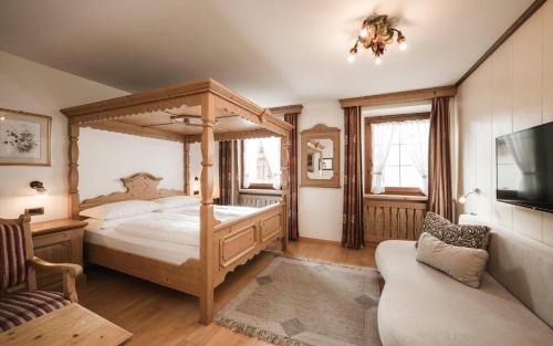 a bedroom with a canopy bed and a couch at Hotel Cavallino D'Oro Bed&Breakfast in Castelrotto
