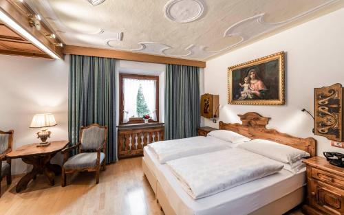 a bedroom with a large bed and a table and a desk at Hotel Cavallino D'Oro Bed&Breakfast in Castelrotto