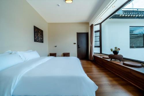 a bedroom with a large bed and a large window at The Whisperer Guanshan Private Residence Hotel in Dali
