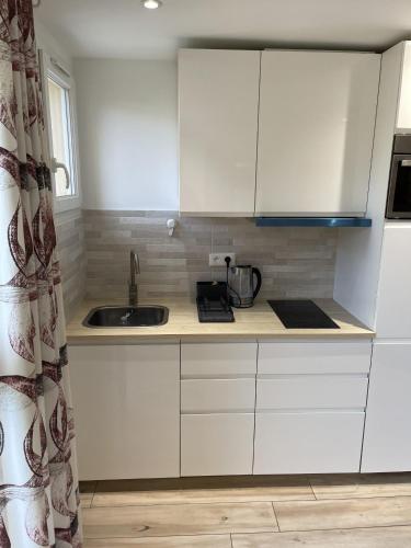 une cuisine avec des armoires blanches et un évier dans l'établissement Magnifique appartement, avec climatisation et parking payants, à Bagneux