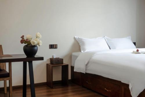 a bedroom with a bed and a table with a vase of flowers at The Whisperer Guanshan Private Residence Hotel in Dali
