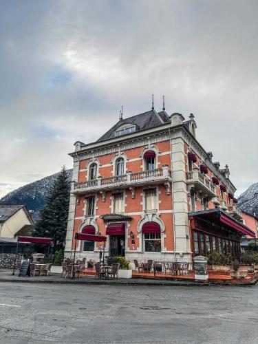 a large brick building with tables and chairs in front of it at Grand Hôtel de France in Pierrefitte-Nestalas