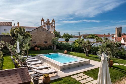 a backyard with a swimming pool and chairs and a building at Villa Alter in Alter do Chão