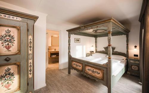 a bedroom with a canopy bed and a bathroom at Hotel Cavallino D'Oro Bed&Breakfast in Castelrotto