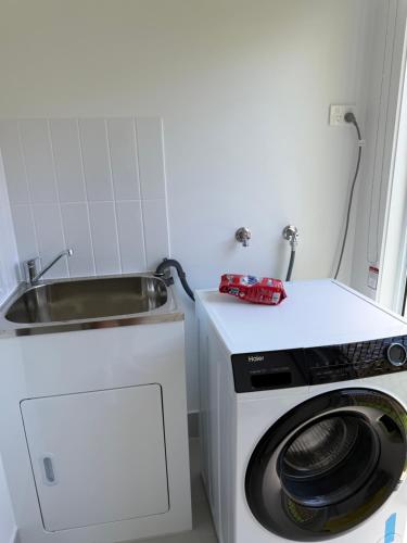 a small kitchen with a sink and a washing machine at Brand New Home - Spacious Family Retreat in Park Ridge