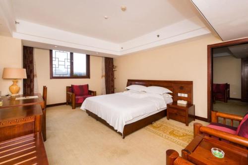 a bedroom with a bed and a desk and chairs at Vienna International Hotel Xi'an Dayan Tower in Xi'an