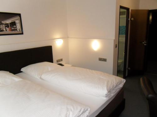 a bedroom with a bed with white sheets at Hotel Gasthof Traube in Kernen