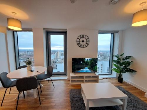 a living room with a table and a tv and windows at Media City Apartment Manchester in Manchester