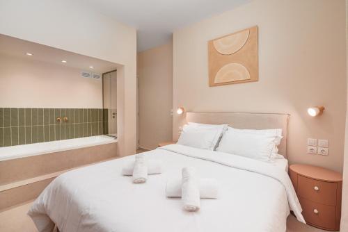 una camera da letto con un grande letto bianco con asciugamani sopra di Koukaki Jacuzzi Retreat ad Atene