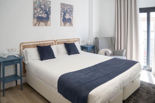 a bedroom with a large white bed with blue pillows at Apartamentos MLC Ciudad de Linares in Linares