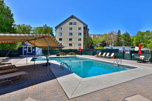 a large swimming pool with a building in the background at Mountain Green 3C16 - Renovated 2BR-2BA With Mountain Views, Hot Tub, Pool, Shuttle, Gym in Killington