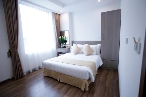a bedroom with a white bed and a large window at The Embassy Hotel Hanoi in Hanoi