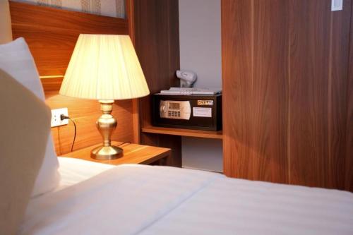 a bedroom with a bed and a lamp on a night stand at The Embassy Hotel Hanoi in Hanoi