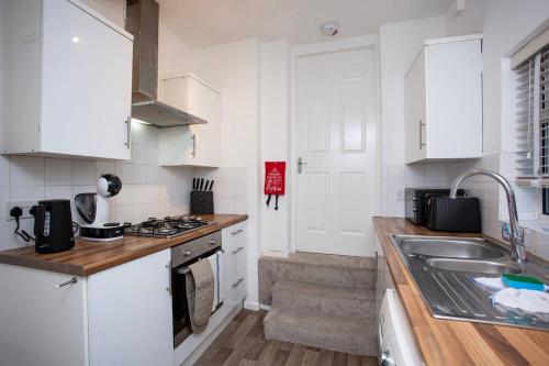 a kitchen with white cabinets and a sink at Vacant Nests - The South View in Whickham