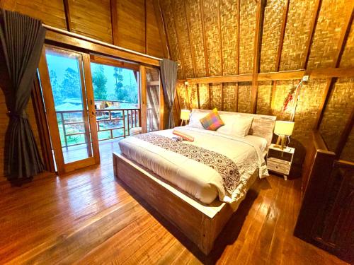 a bedroom with a bed in a room with wooden floors at Bali Cottages Lake View in Kintamani